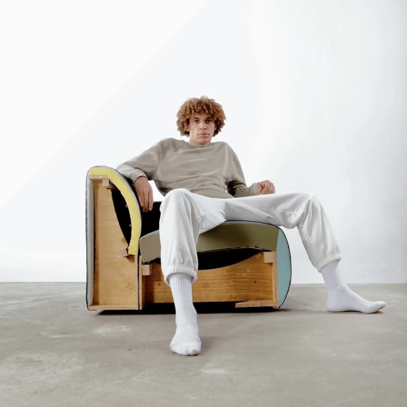 Young man sitting on cross-section armchair that shows the frame components