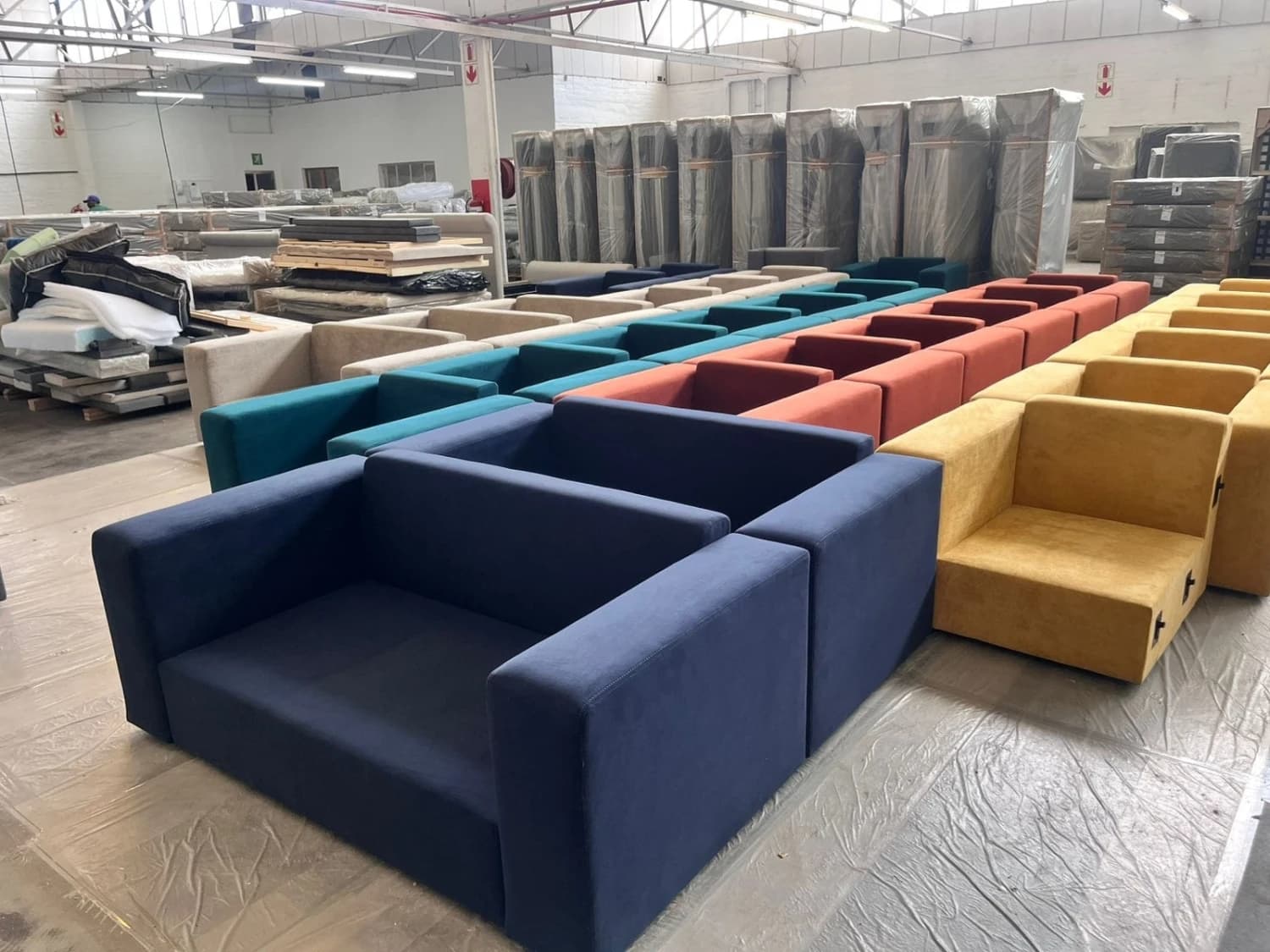 3 rows of blue, red and yellow Scooch sofas and armchairs fill the warehouse before delivery to the G20 summit